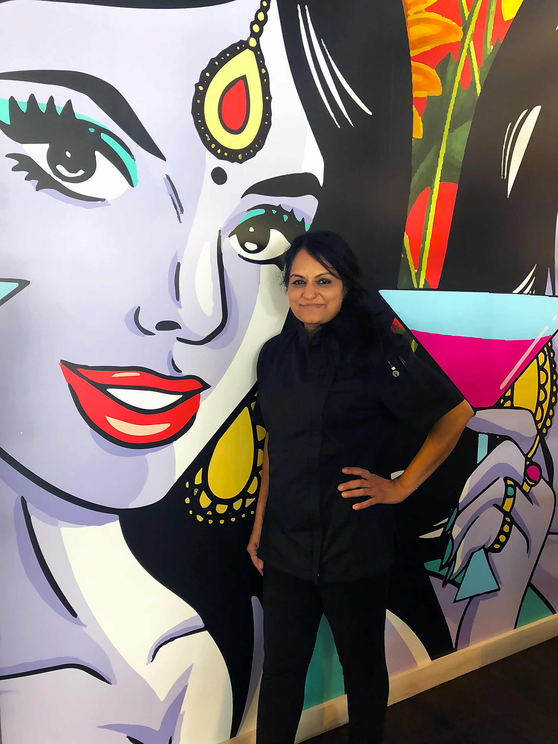 Chef and Partner Heena Patel in front of pop-art mural by HateCopy’s Maria Qamar