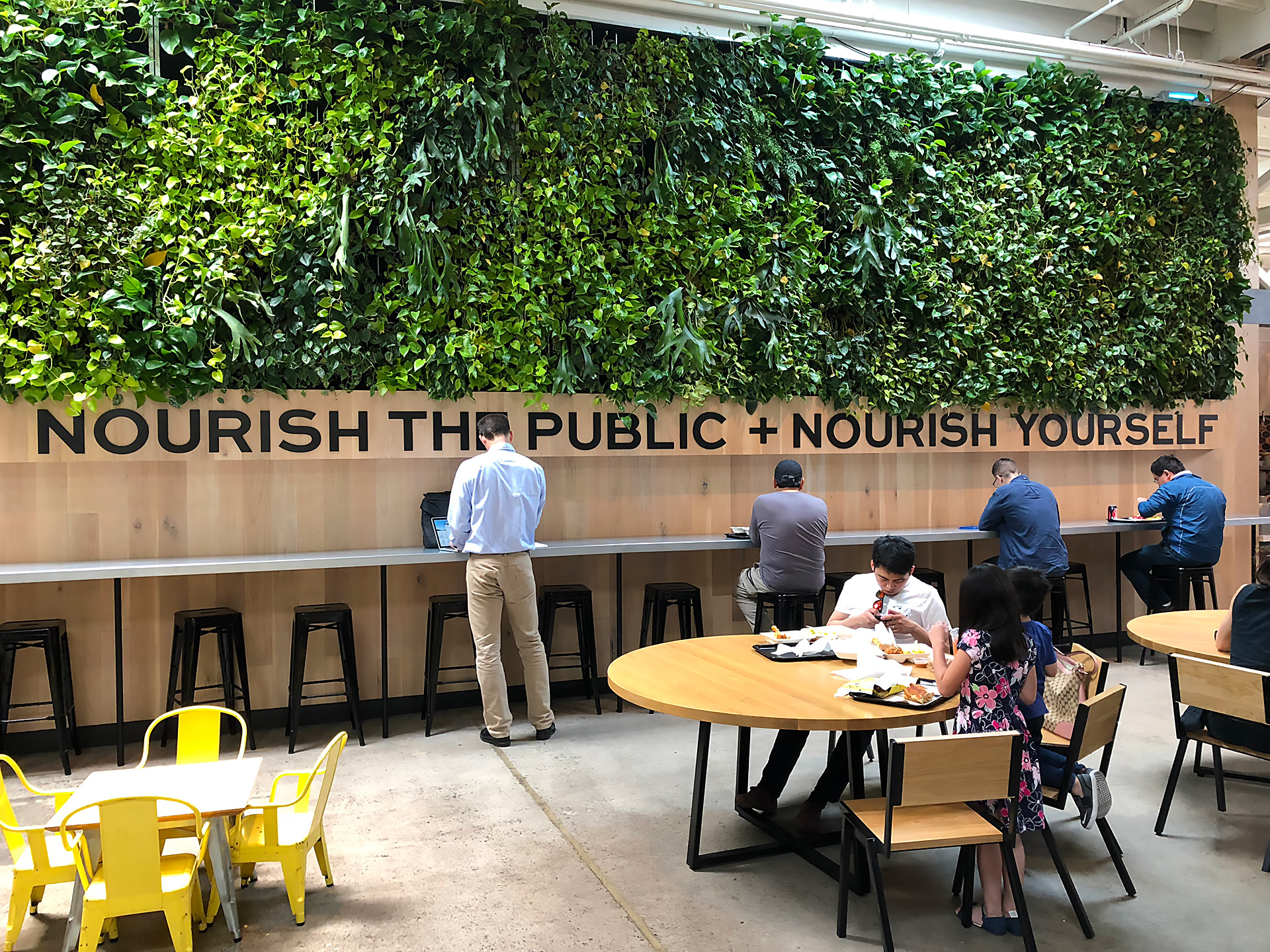 "Nourish The Public + Nourish Yourself" signage at The Emeryville Public Market next to Minnie Bell's kiosk.