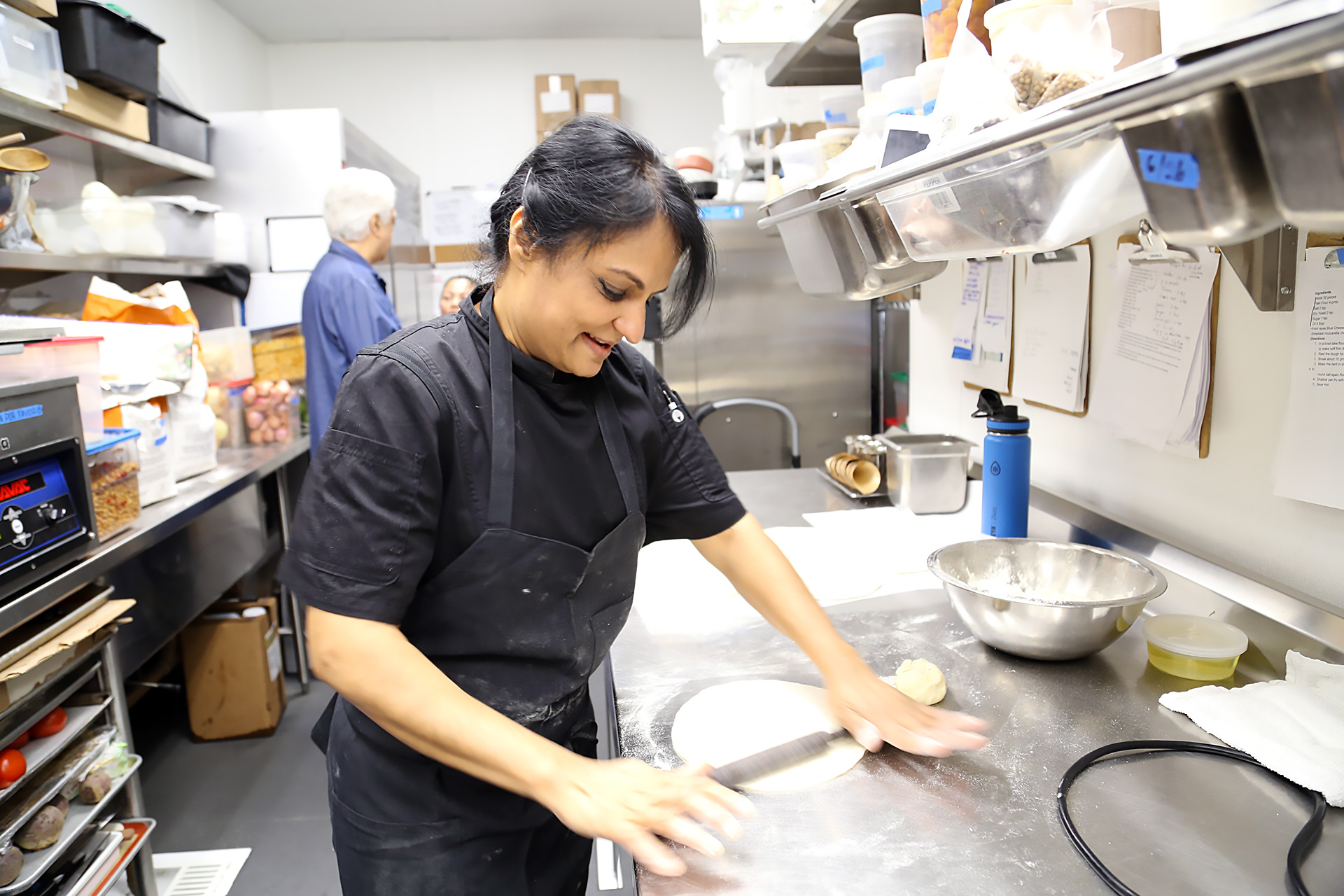 Heena Patel rolls dough for flatbread in back kitchen.