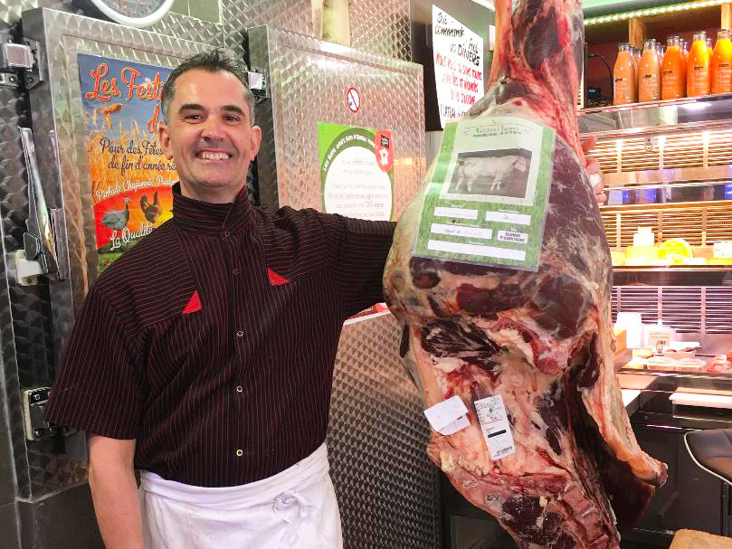 Tass poses with the carcass of a Blonde d'Aquitaine cow. The butcher has papers that include when and where it was born, raised, where it was slaughtered and its vaccinations.
