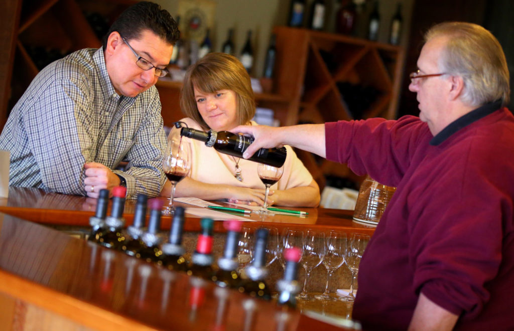 Tasting room manager Gary Gross, right, pours a 2009 Vintage Port for Bernadette and Eduardo Gamez, from Chandler, Arizona, at Pedroncelli Winery, in Geyserville on Thursday, November 13, 2014. 