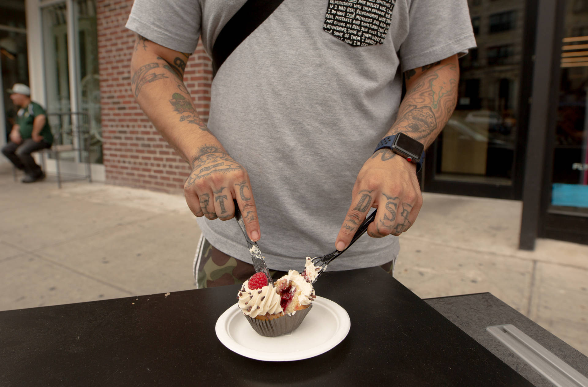 Castro digs into a vegan raspberry cupcake on a discarded desk outside of By Chloe.