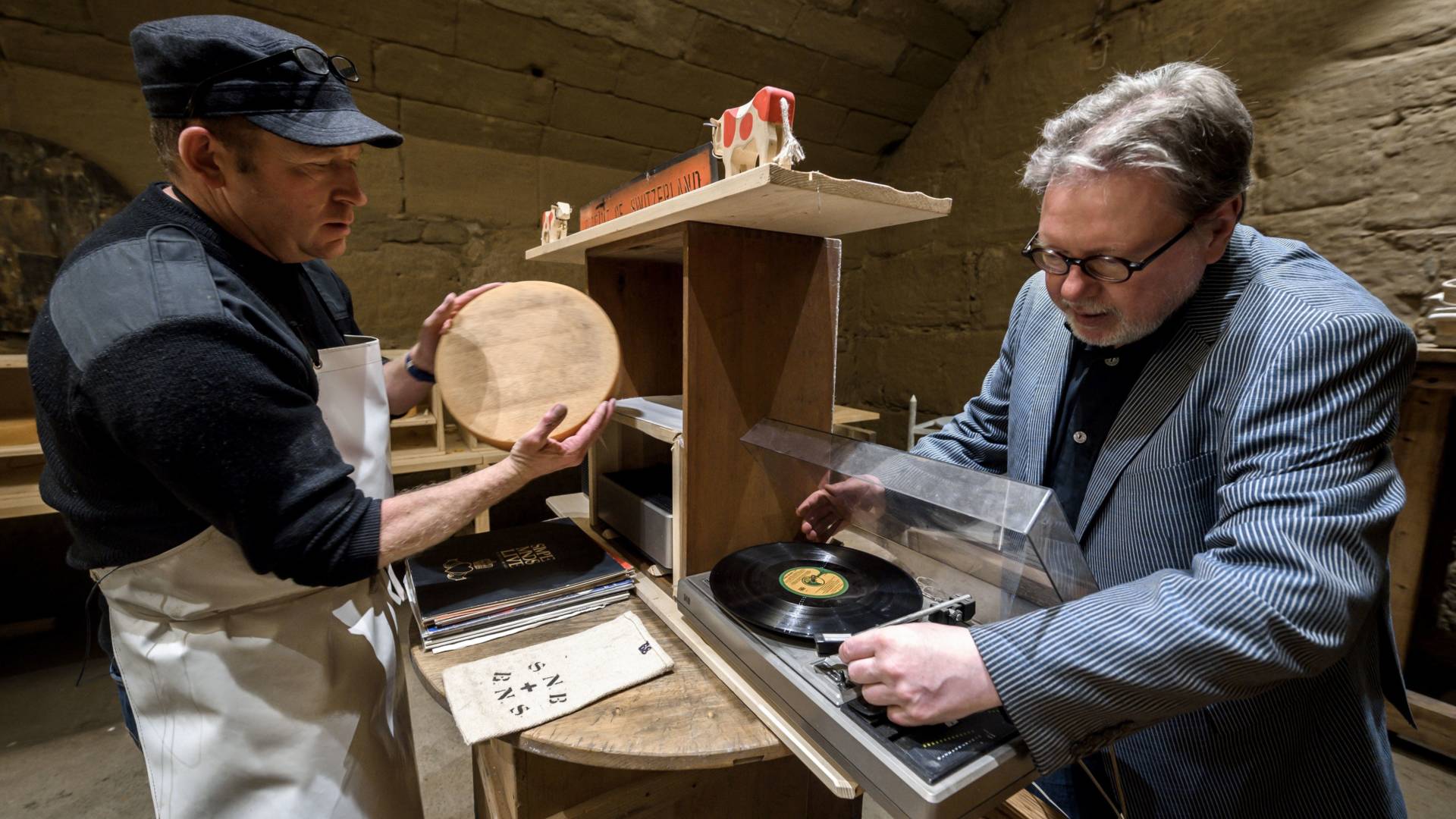 Swiss cheesemaker Beat Wampfler, left, and director of the Music Department at University of the Arts in Bern, Michael Harenberg pose with a vinyl record and a wheel of Emmental.