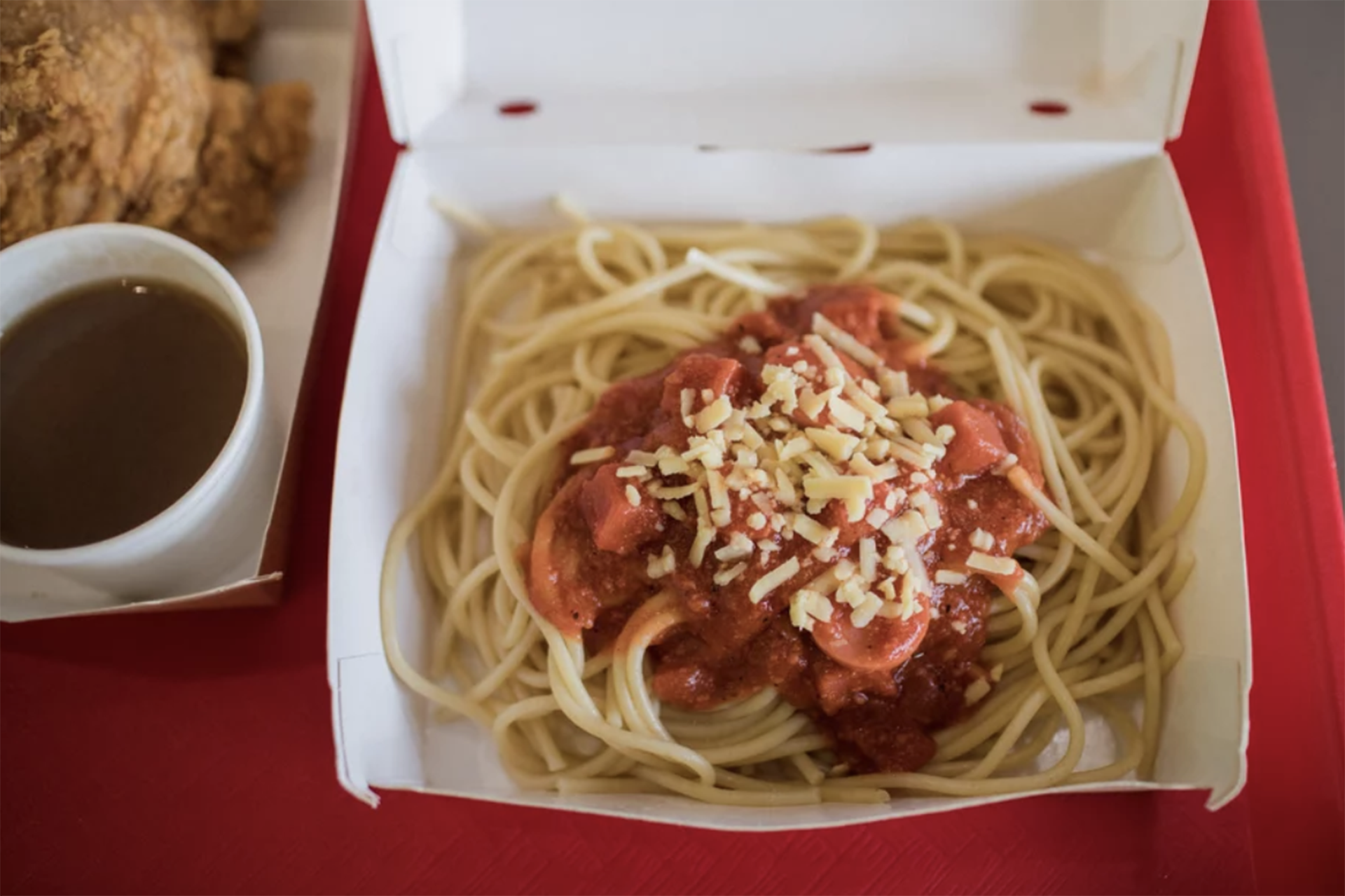 Filipino spaghetti, often sweeter than American spaghetti, is made with slices of hot dogs and served with a side of Chickenjoy at Jollibee.