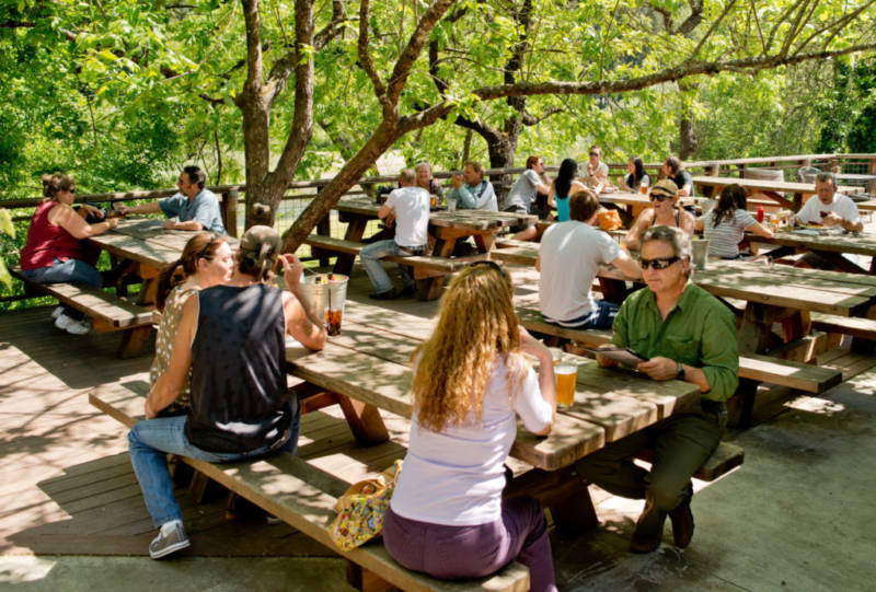 Guests enjoying cold drinks on the patio overlooking the Russian River at Stumptown Brewery.