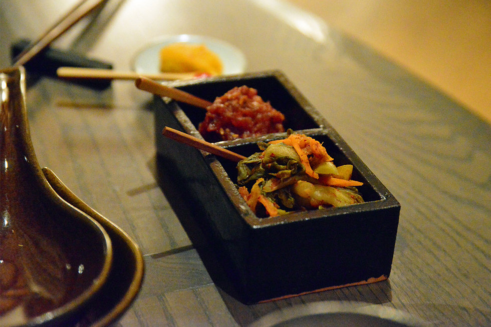 The donabe was accompanied by several small, unique ceramic pieces, each with a different condiment.