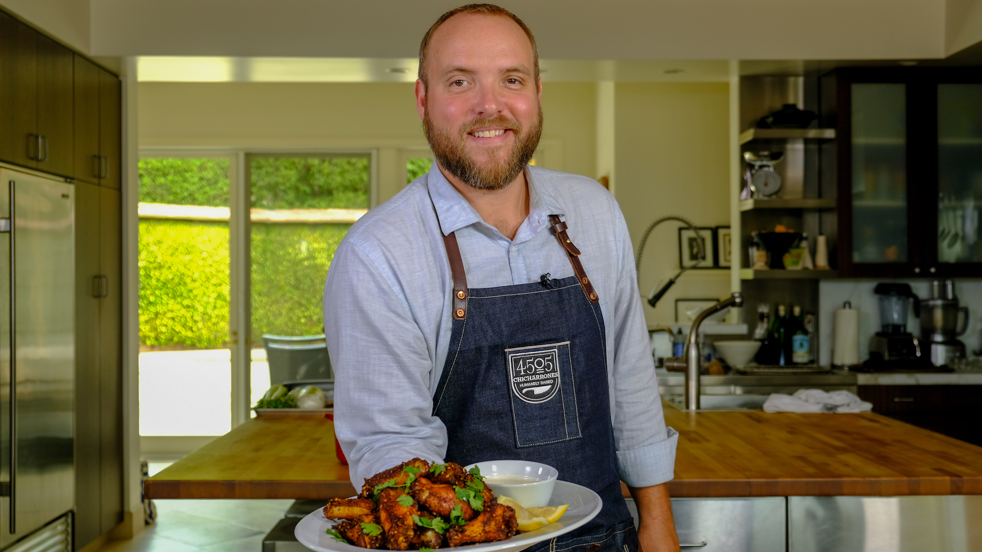 Chef Ryan Farr holds a plate of his Harissa Wings with a side of Alabama White BBQ Sauce.