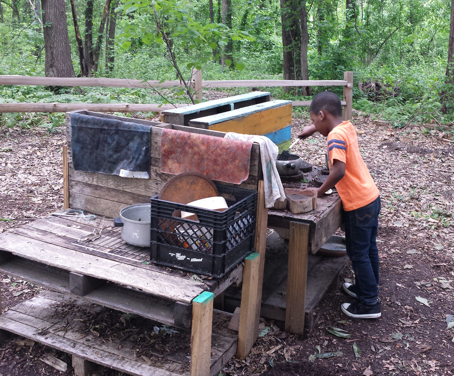 A student cooks a meal using an outdoor kitchen in the Little Creek Nature Area's Discovery Classroom. 