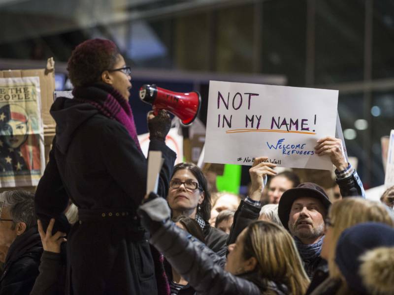 A woman uses a megaphone to address a crowd of protesters at Boston's Logan International Airport on Saturday.