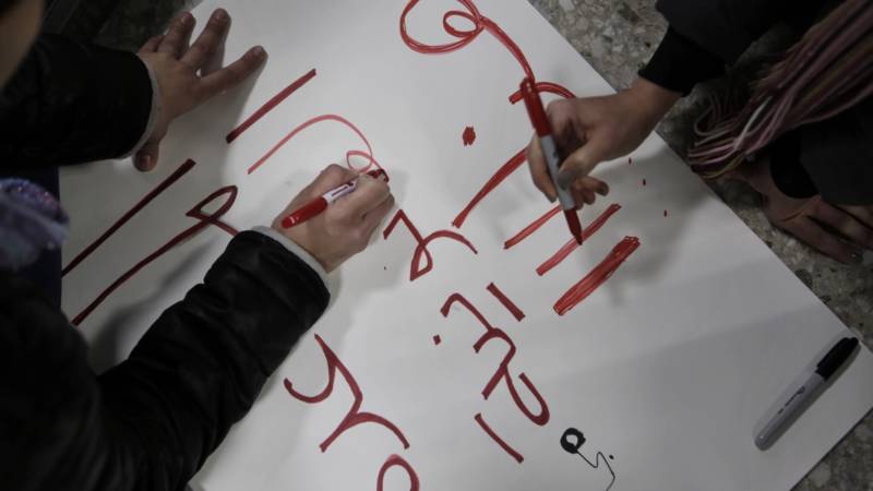 Volunteers at Dulles International Airport outside Washington, D.C., make a sign in Arabic on Sunday, which reads "free legal help."