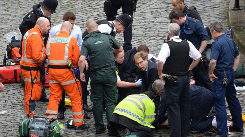 Conservative MP Tobias Ellwood helps emergency services attend to a police officer outside the Palace of Westminster, London, after a policeman was stabbed and his apparent attacker shot by officers in a major security incident at the Houses of Parliament.