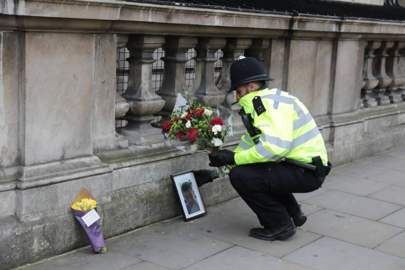 A police officer places flowers from a member of the public next to a photo of Keith Palmer, the police officer who was stabbed Wednesday as he guarded the Palace of Westminster. Prime Minister Theresa May said of Palmer, "He was every inch a hero."