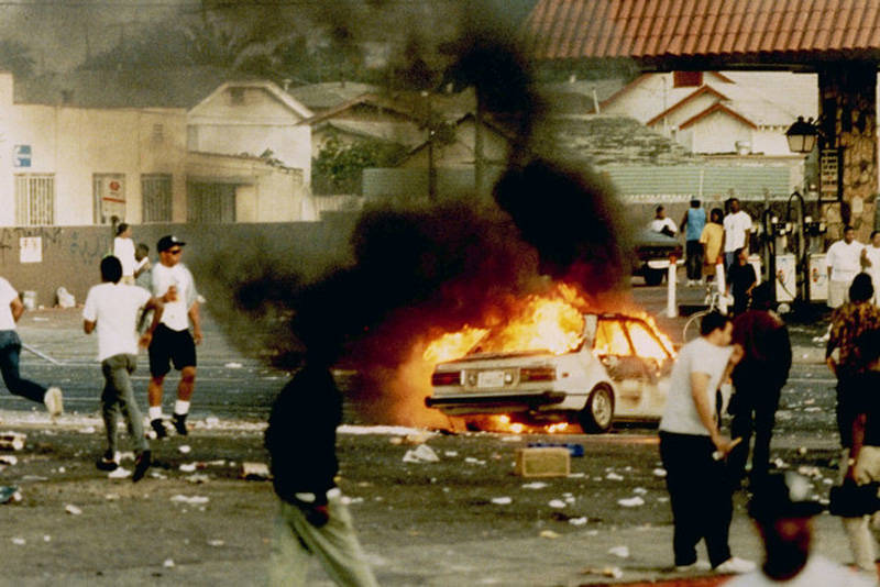 A car burns as looters take to the streets at the intersection of Florence and Normandie avenues — considered the flashpoint of the LA riots — on April 29, 1992.