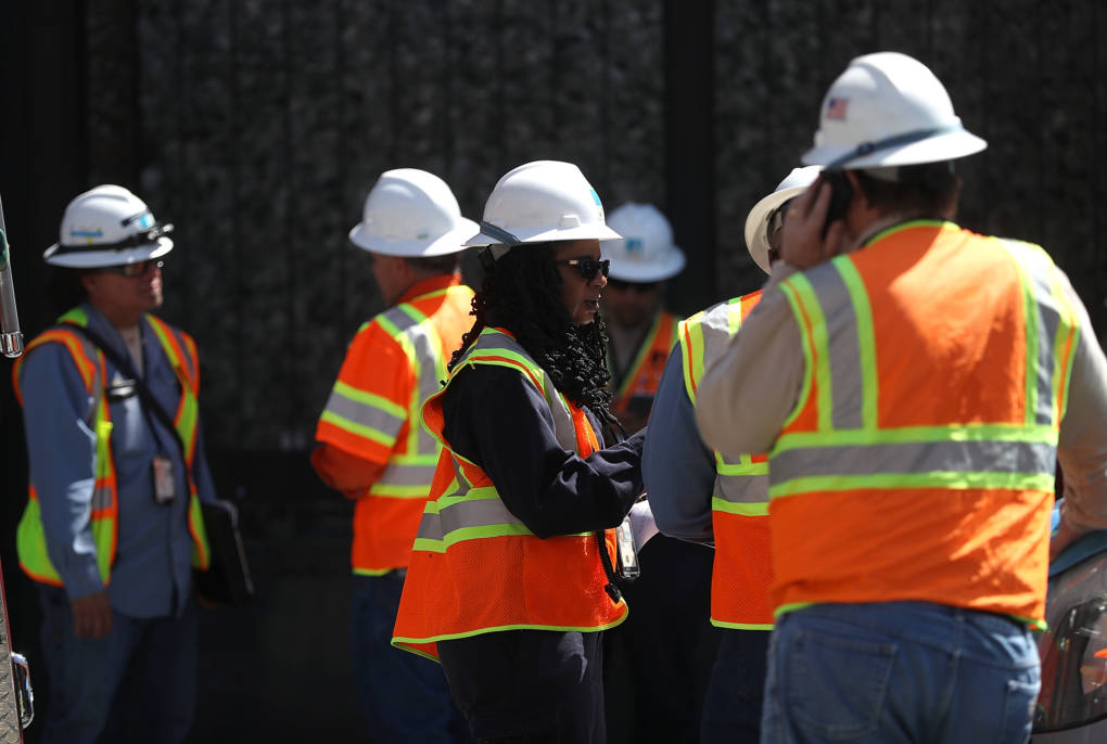 PG&E workers stand outside of an electric substation where a fire occurred and might have caused the outage.