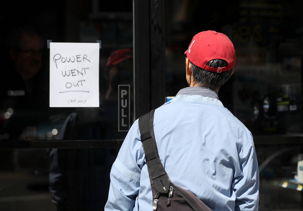 A pedestrian looks at a sign posted on the door of a hardware store.
