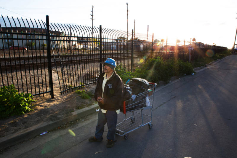 A man rests from pushing his cart as the sun sets behind the railroad tracks in Salinas' Chinatown.