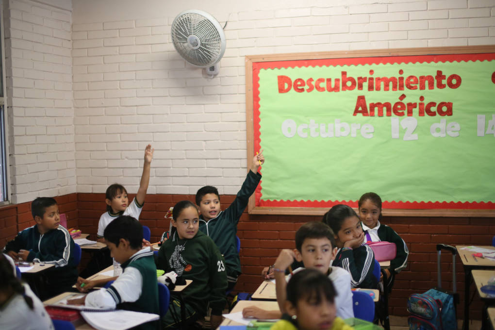 Students raise their hands at the Escuela 20 Noviembre school in Tijuana, Mexico.