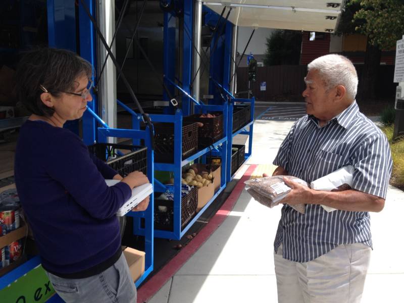 Grocery truck volunteer and recipient Iraneo Garcia chats with Mercy Brown Bag Program Assistant Director Nicole St. Lawrence about how to cook lentils.