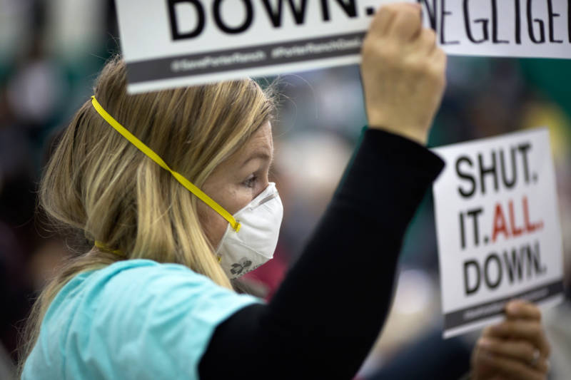 A woman holds a sign at a public hearing before the South Coast Air Quality Management District (AQMD) regarding a proposed abatement order to stop the massive Aliso Canyon natural gas leak, on January 16, 2016, near Porter Ranch.