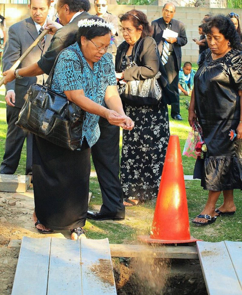 Greta Briand attends a Marshallese funeral and scatters dirt over a grave. Her younger sister, Delta Garstang, far right, is a thyroid cancer survivor.