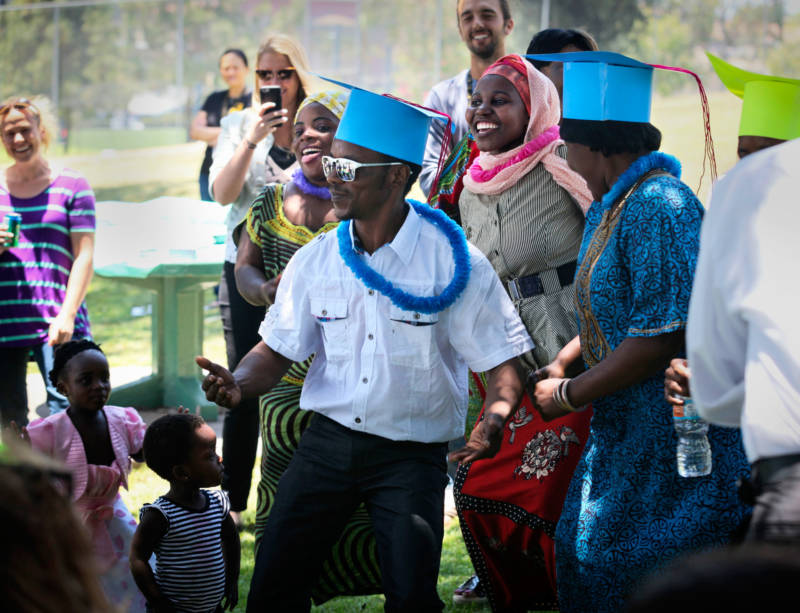 Ramazani Ali leads refugees in a graduation dance at a San Diego park. His wife, Zawadi, is behind him in a yellow headscarf.