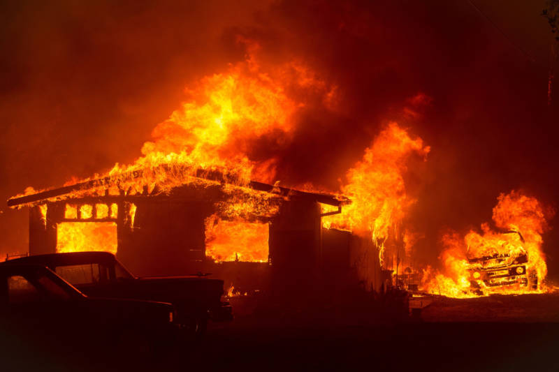 A car and house are engulfed in flames as the Wall Fire burns through a residential area in Oroville on July 8, 2017.
