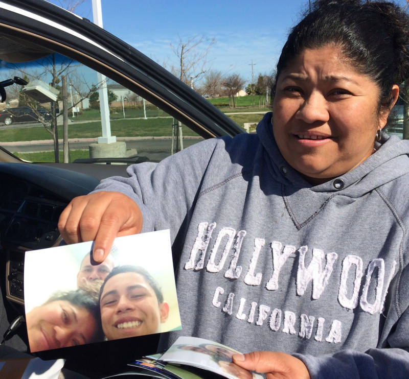 Evelyn Aguilar holds up a photo of herself visiting with her son, Pablo, when he was detained at a facility in Oregon in 2015. Her friend, Mario, is in the background.