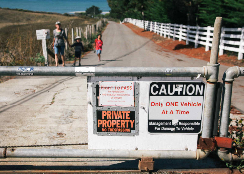 A 'Private Property: No Trespassing' sign on a closed gate leading to Martins Beach.