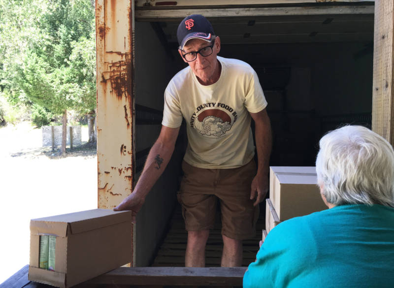 Jeff England unloads boxes at his last stop, Ruth Lake. Site supervisor Sandy Rasche says 45 families come to get food. The local population hovers around 200.