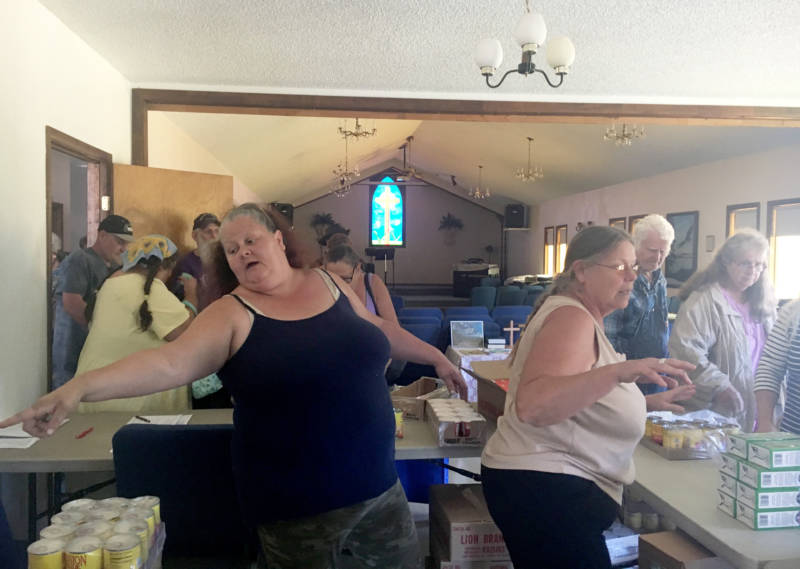 Volunteers Christen Hutchason and Teresia Kirkland hand out food to more than 50 people at Solid Rock Church in the former mill town of Hayfork.