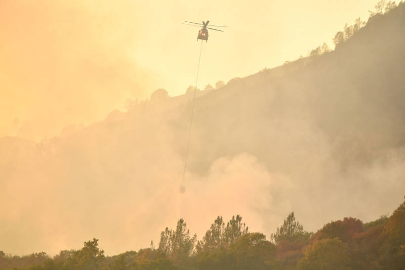 A helicopter drops water on flames in Calistoga on October 11, 2017.