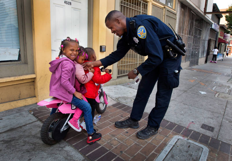 Officer Rodney Freeman passes out stickers on Third Street in the Bayview, where many black residents live. So many families have left the city due to its high cost of living that it now has a lower percentage of children than any other major U.S. city.