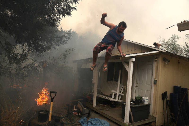 A resident rushes to save his home as an out-of-control wildfire moves through the area on October 9, 2017 in Glen Ellen.