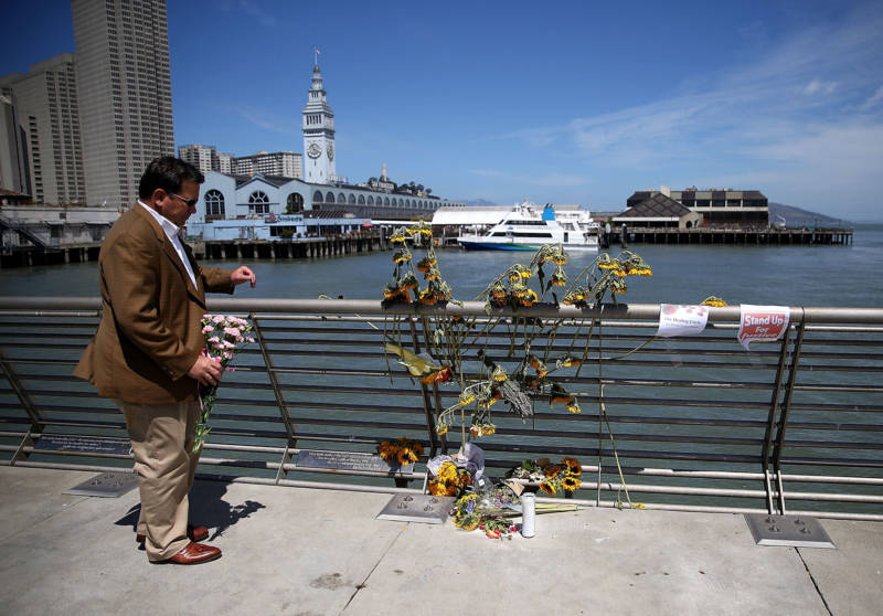A well-wisher drops off flowers at the site where 32-year-old Kathryn Steinle was killed on Pier 14 in San Francisco.