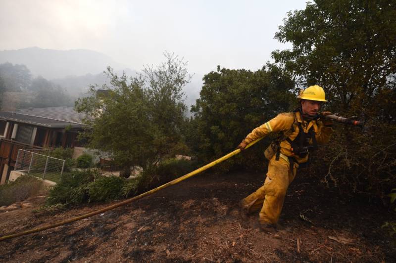 Napa City firefighter Nick Rizzo pulls a hose up a steep hill to protect structures from the Thomas Fire on December 16, 2017 in Montecito, California.