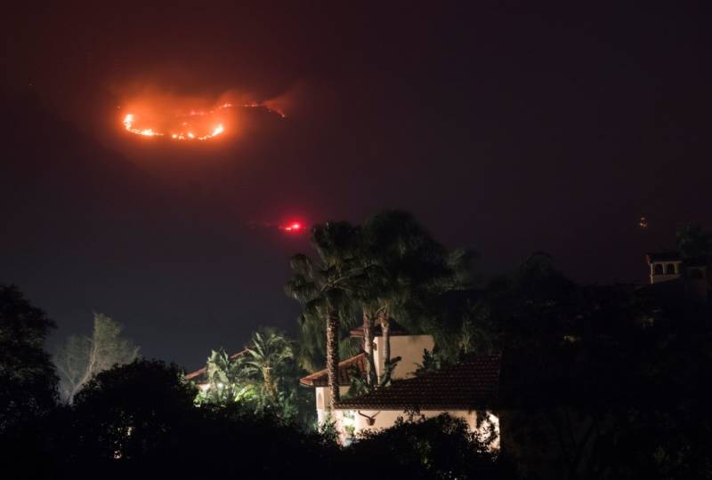 Fire burns in the hills behind a home at the Thomas Fire, December 16, 2017 in Montecito, California.