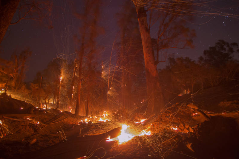 A strong wind blows embers from smoldering trees at the Thomas Fire on December 16, 2017 in Montecito, California.