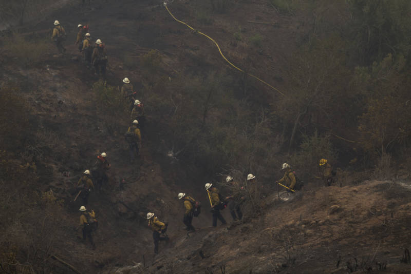 A Hot Shot crew marches through a canyon between homes to fight the Thomas Fire on December 16, 2017 in Montecito, California.