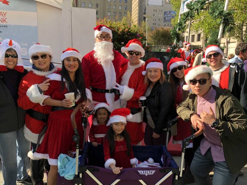 Philip Jang (center with beard), Jenny Jang (to his left) and their daughters Jasmine and Tiffany Jang (in the cart) celebrate SantaCon 2017 with friends at San Francisco's Union Square. Philip says the girls already had their Santa outfits but he and Jenny had to buy new ones for the event.