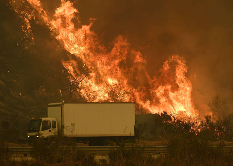 Vehicles pass a wall of flame on the 101 freeway as the Thomas Fire reaches the coast near Ventura on Dec. 6, 2017. 