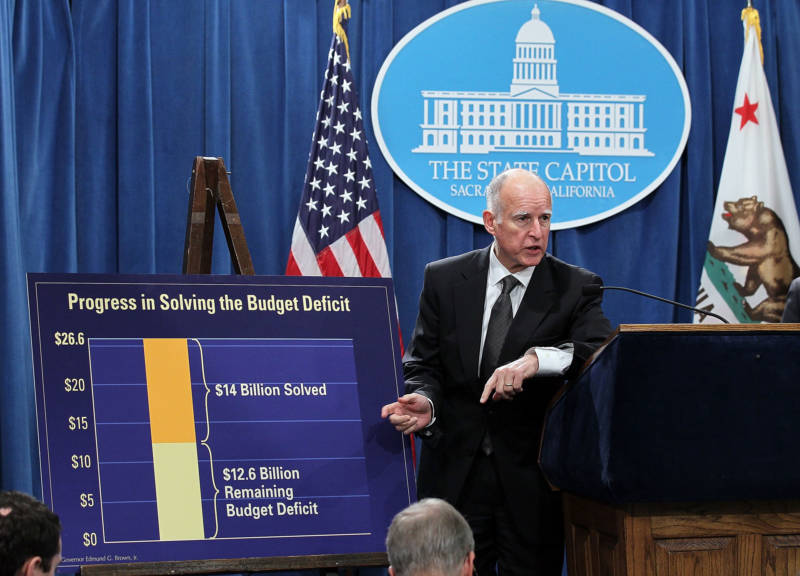 Gov. Brown points to a chart showing dollar amounts in the billions that were cut from the state budget following a bill signing on March 24, 2011.