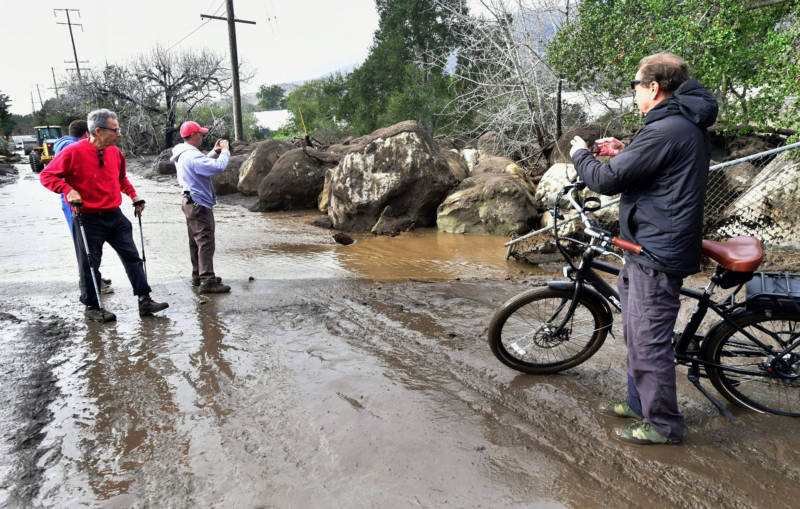 Residents have a look at boulders which were carried down nearby hillsides by flooding in Carpinteria on January 9, 2018.