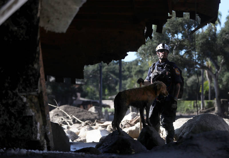 An urban search and rescue team member and his dog search a home that was destroyed by a mudslide on January 11, 2018 in Montecito.