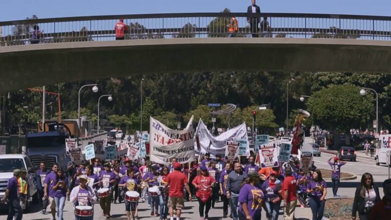 Janitors march with signs saying "Ya Basta!" or "Enough is Enough!" to encourage the passage of new laws protecting workers from sexual abuse.