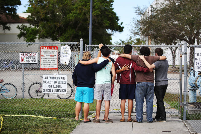 People look on at the Marjory Stoneman Douglas High School on February 18, 2018 in Parkland, Florida. Police arrested 19 year old former student Nikolas Cruz for the mass shooting that killed 17 people on February 14.