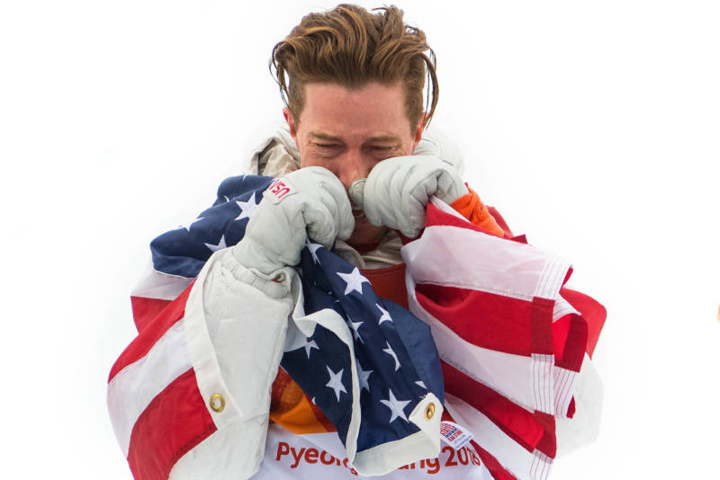 U.S. snowboarder Shaun White wraps himself in the U.S. flag after winning gold in the men's halfpipe. He was later criticized for dragging a flag on the ground.