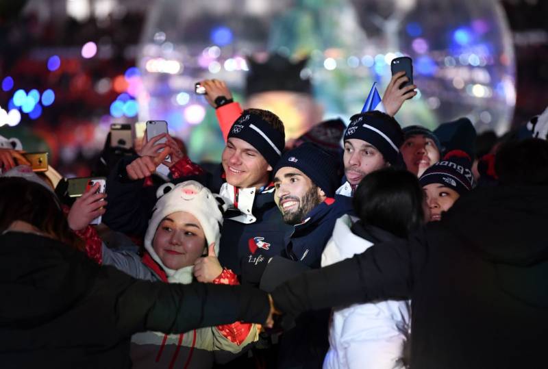France's biathlon champion Martin Fourcade (center), who won three gold medals in Pyeongchang, poses for a selfie with athletes and volunteers during the closing ceremony.