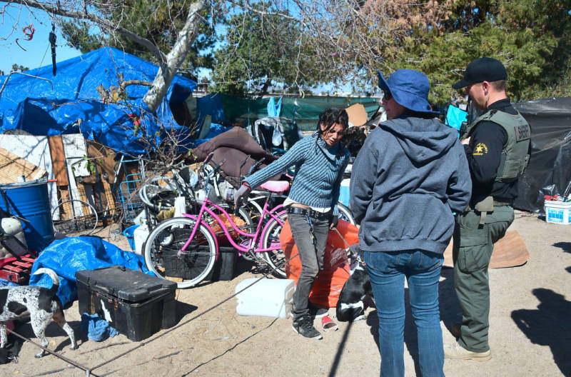 An officer from the Sheriff's Department and a social worker speak with a woman at the homeless encampment beside the Santa Ana River in Anaheim on February 20, 2018.
