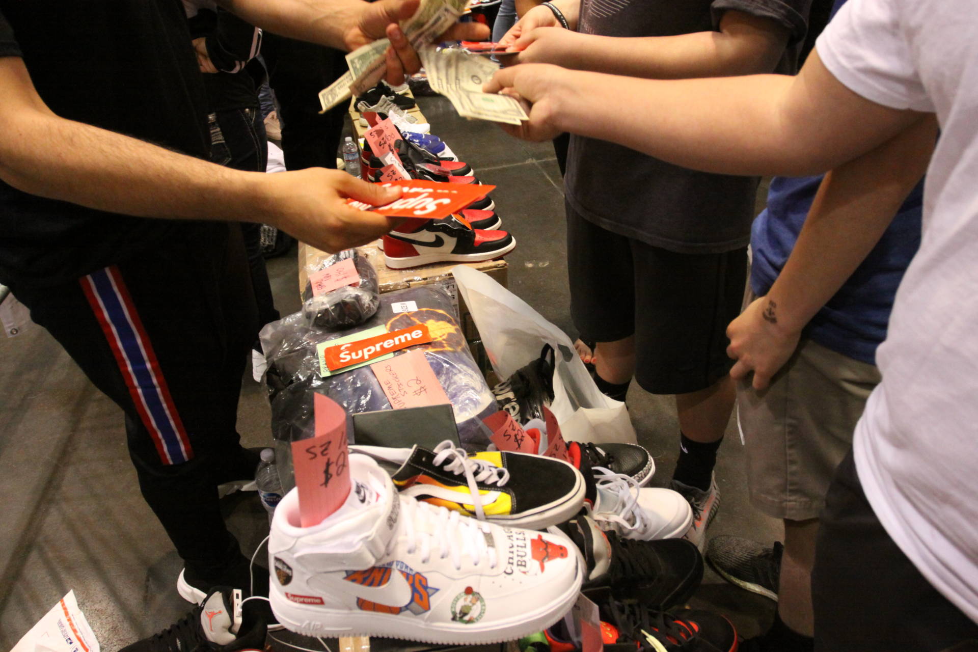 Buyers and sellers exchange goods for cash on the Sneaker Con Trading Pit floor.