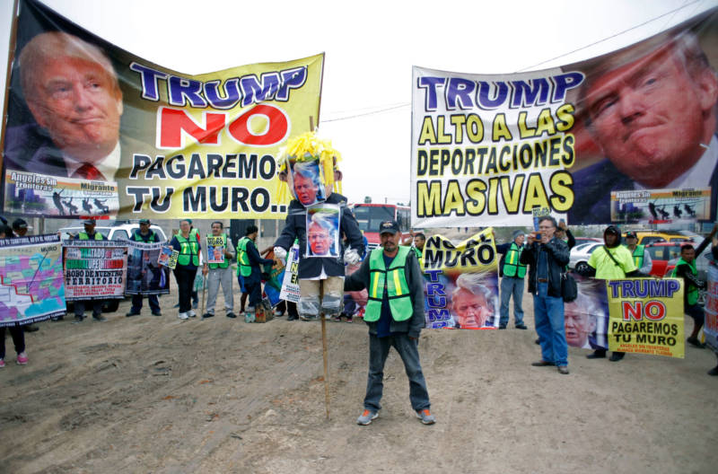 Demonstrators protest against President Donald Trump's migration policies on the Mexican side of the border in Tijuana on March 13, 2018, as President Trump toured border wall prototypes.